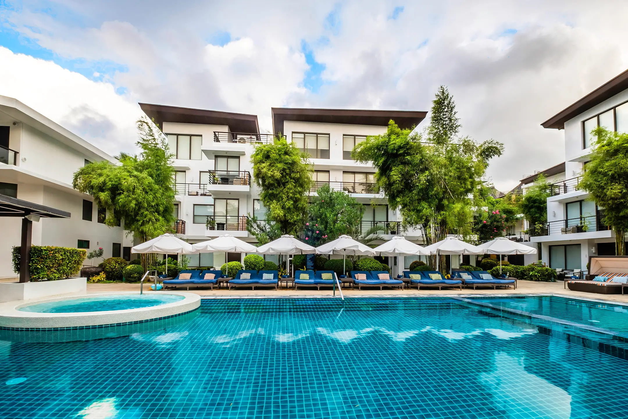A spacious swimming pool surrounded by white sun umbrellas and lounge chairs at Discovery Shores Boracay, one of the best boutique resorts in Boracay