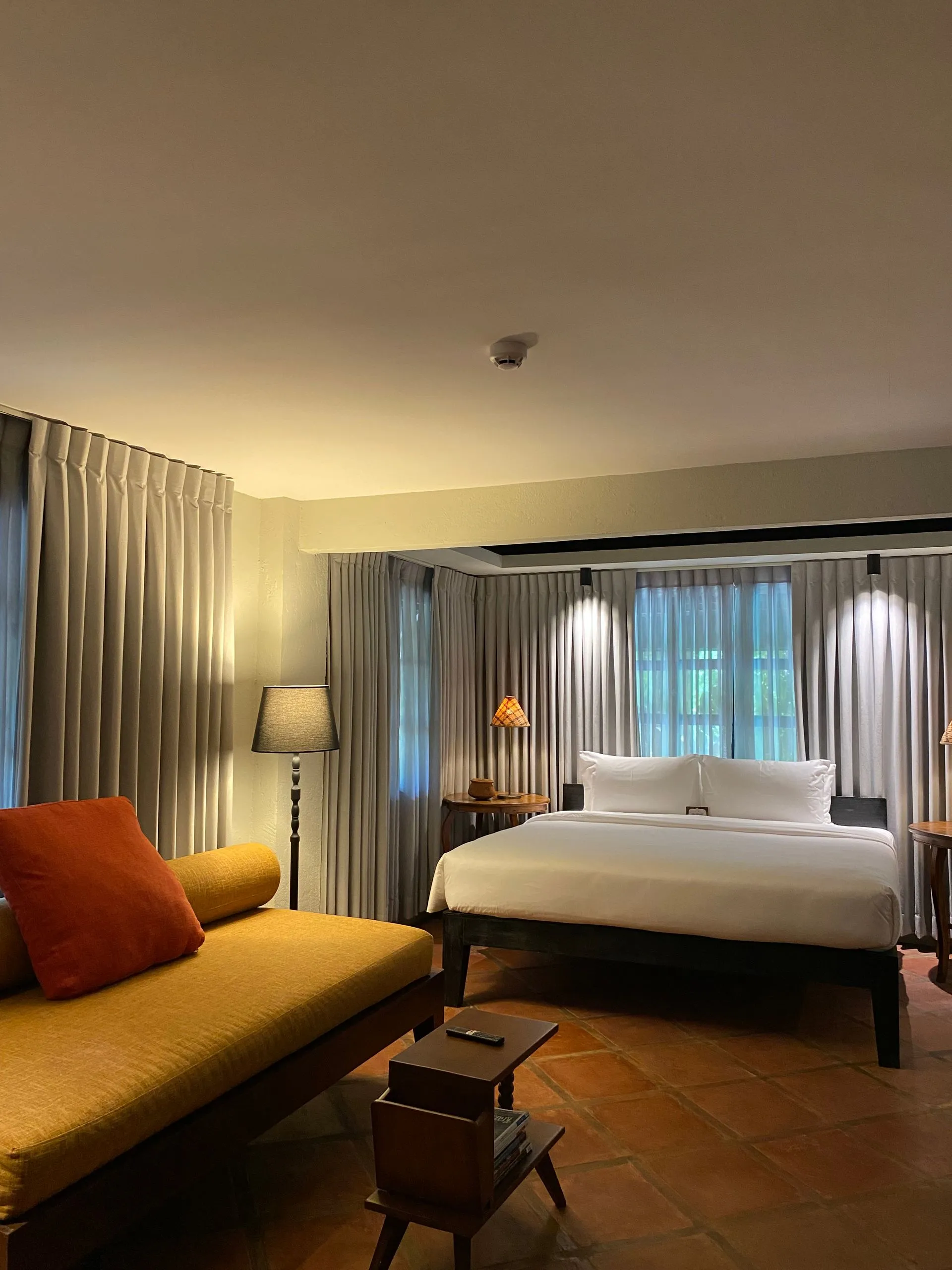 Warm and inviting guest room at The Henry Resort Boracay, a boutique hotel in Boracay, showcasing a plush bed with bright orange accents, elegant drapery, and a relaxed seating area.