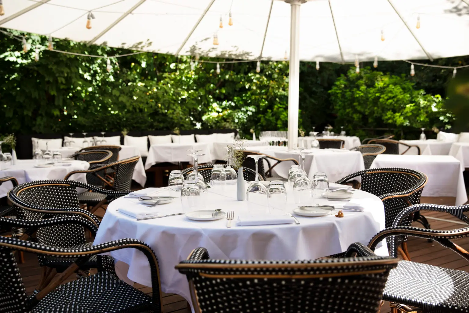 Outdoor dining area with white tablecloths and wicker chairs at Villa9Trois, a Michelin Star restaurant in Paris