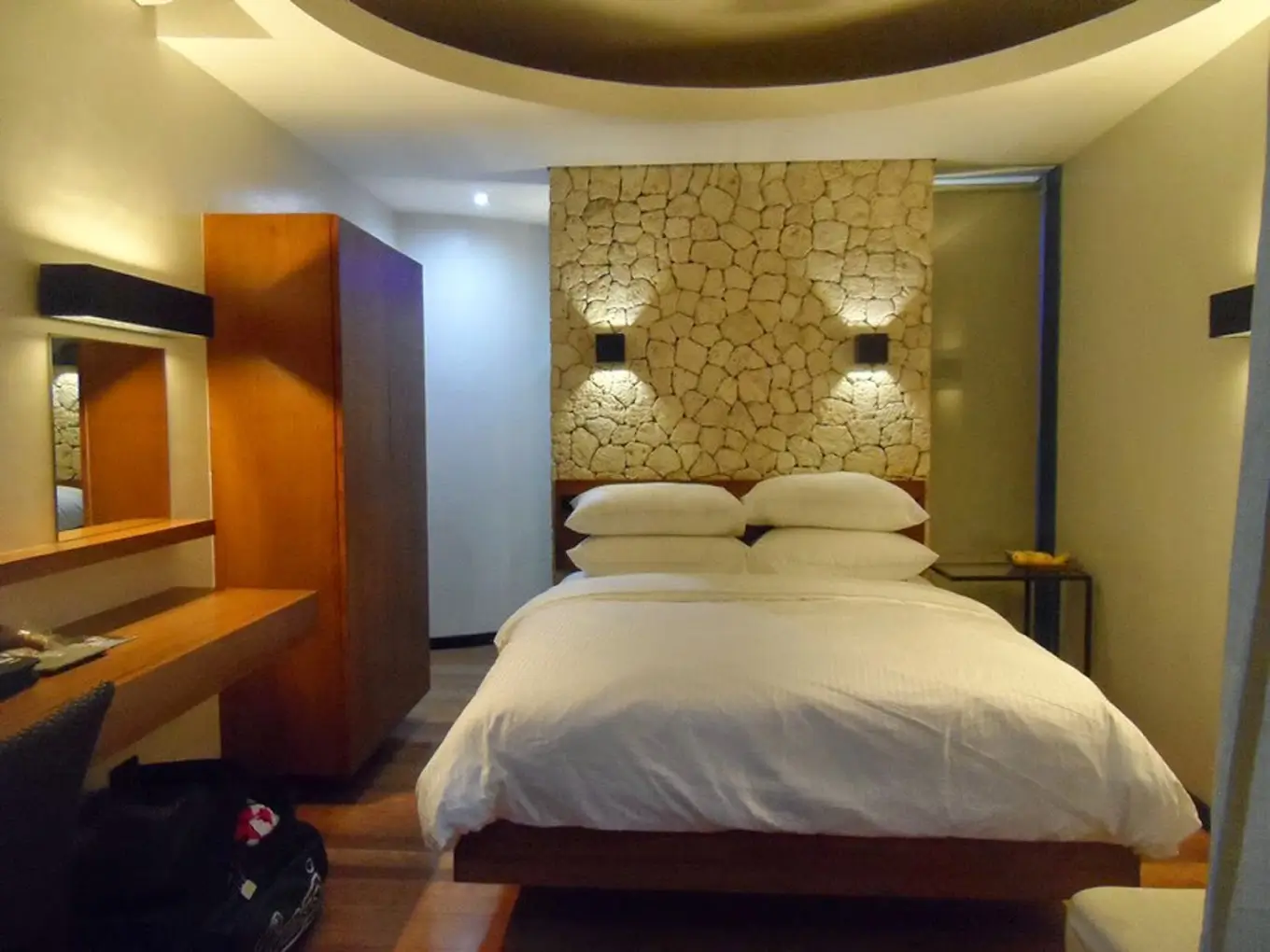 Elegant guest room at WaterColors Boracay Dive Resort, a boutique hotel in Boracay, featuring a king-sized bed with a unique stone accent wall and modern furnishings.