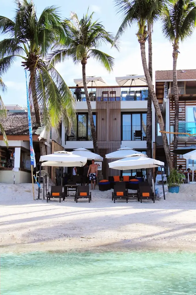 Comfortable beach lounging area at WaterColors Boracay Dive Resort, a boutique hotel in Boracay, with umbrella-shaded seating on the white sandy beach.