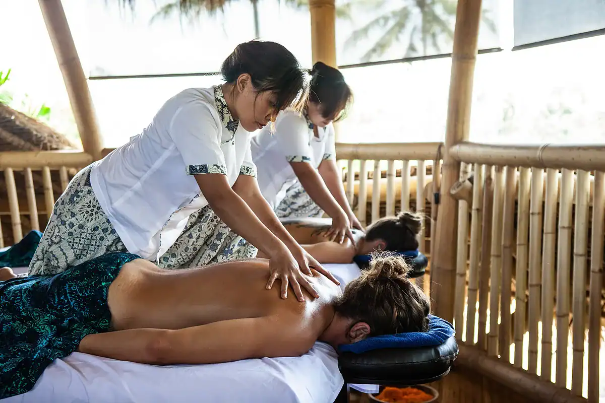 Two therapists giving massages to guests in a bamboo pavilion at the Blue Karma detox retreat in Ubud, Bali
