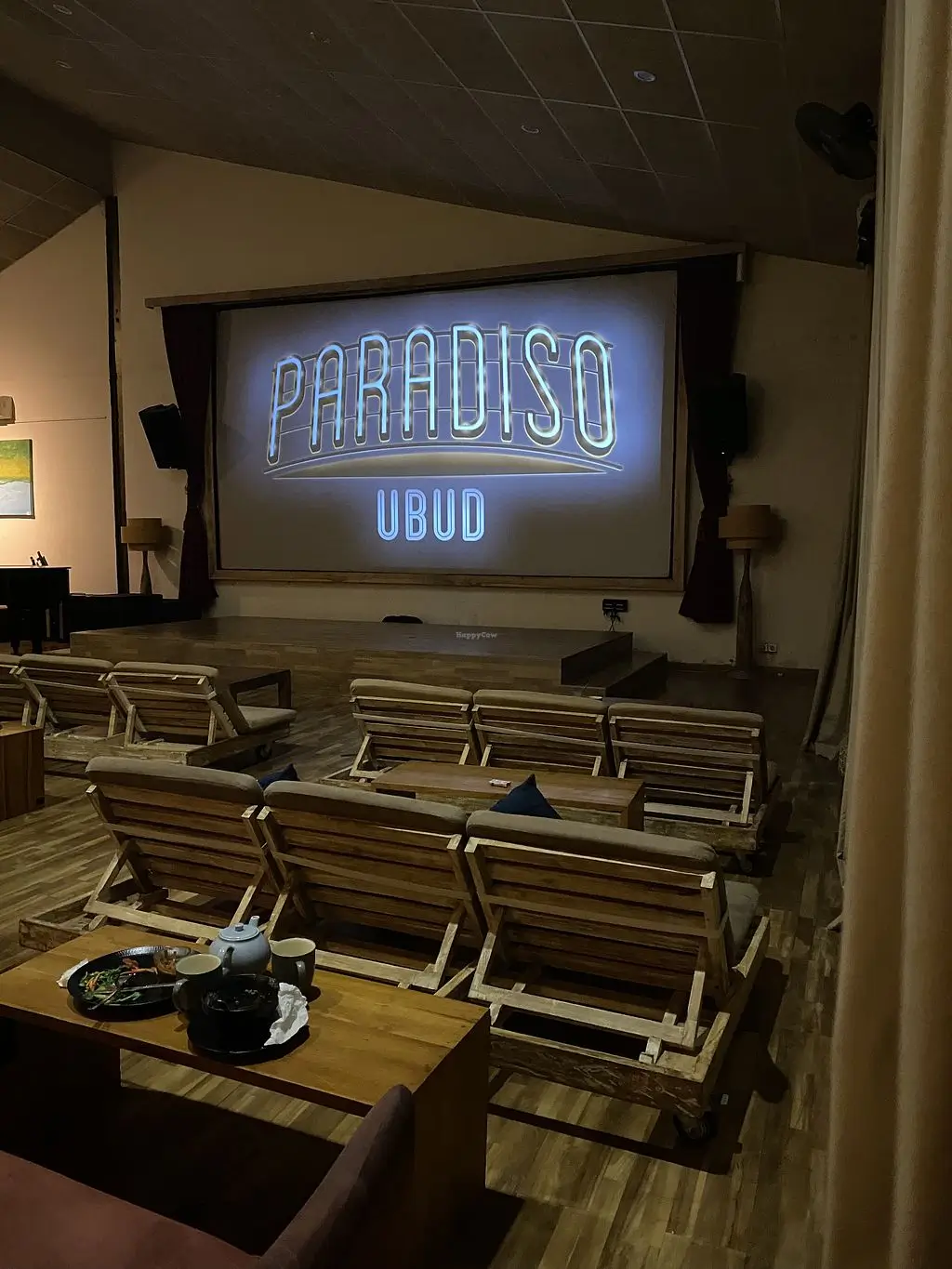 Cinema of Paradiso Ubud with comfortable chairs and a large screen with Paradiso Ubud logo on it