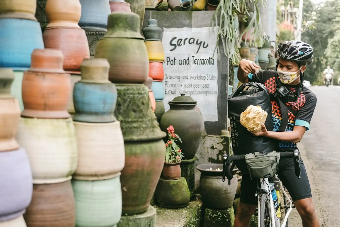 A rider putting a wrapped pot on his bag with different kinds of pots in the background