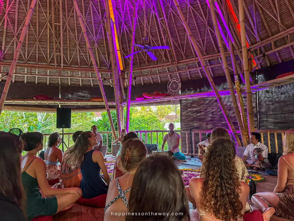 A group of people sitting inside a colorful bamboo structure in Ubud, participating in a kirtan session, one of the spiritual things to do in Bali.