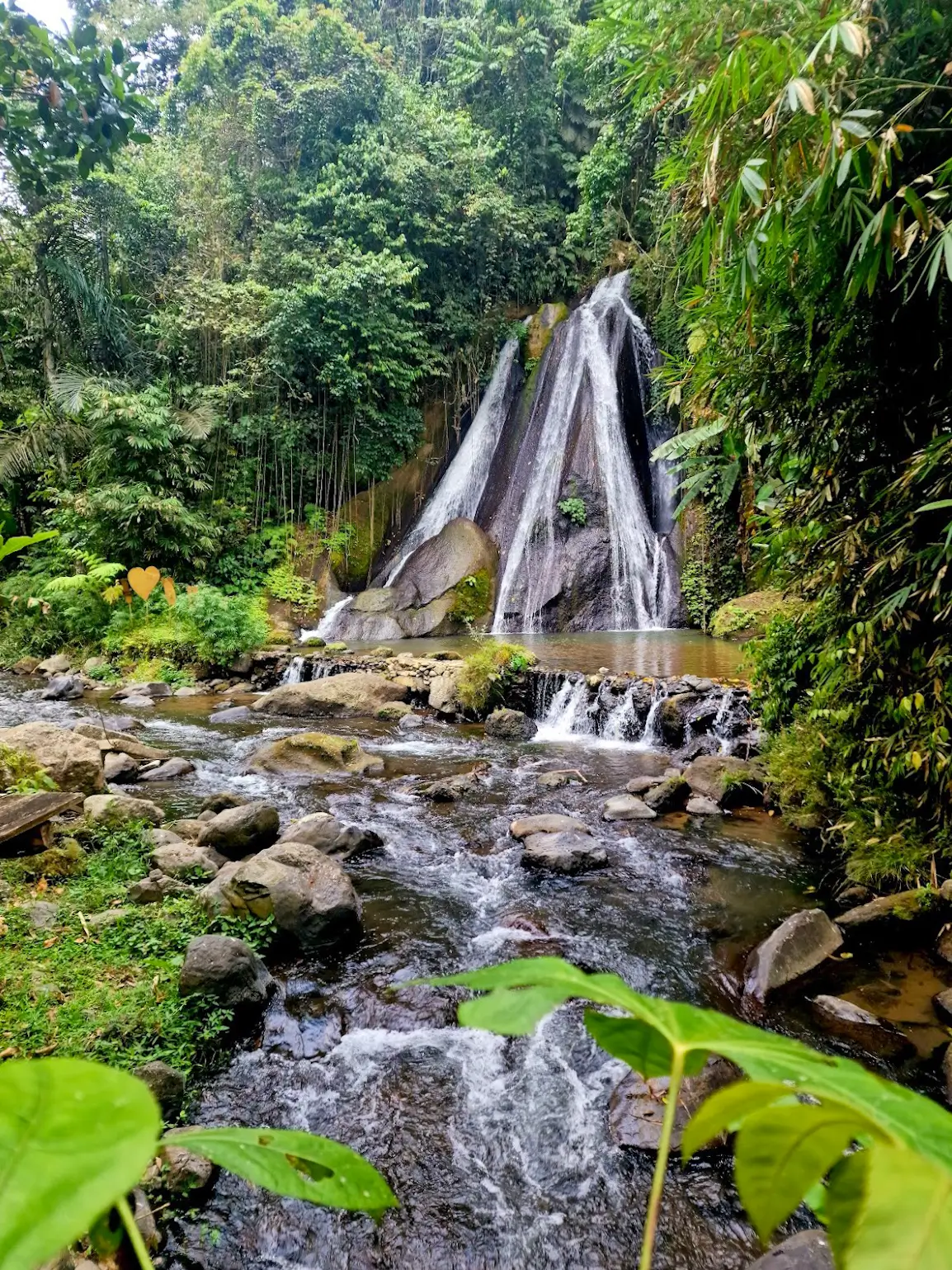 Campuhan waterfall flowing into rocks and a river inside a forest