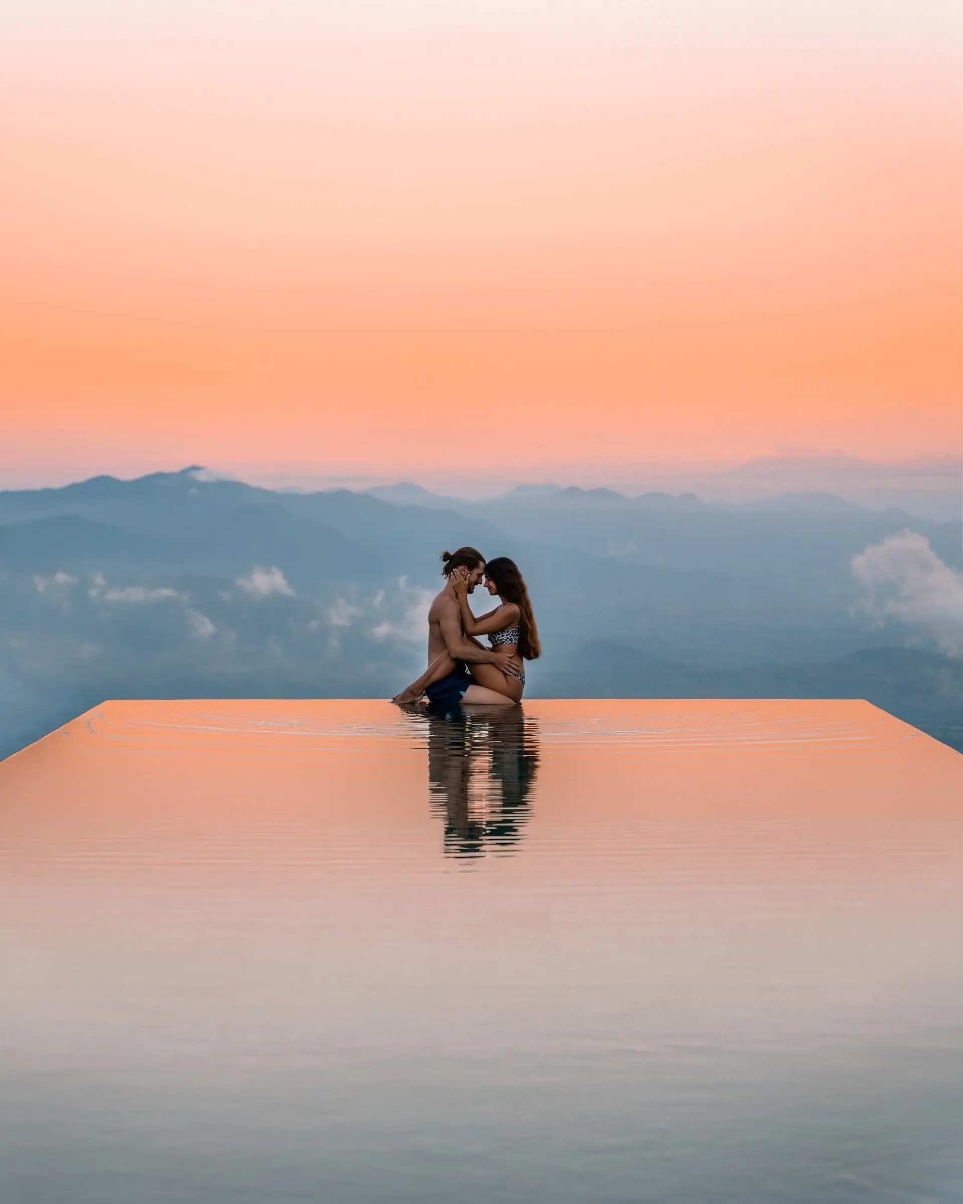 A couple in an infinity pool with orange sky