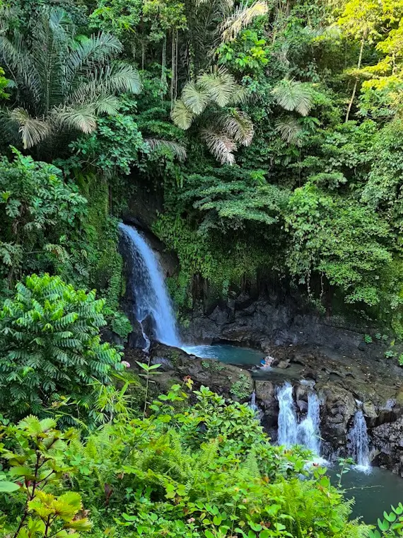 Taman Sari waterfall, surrounded by lush tropical forest.