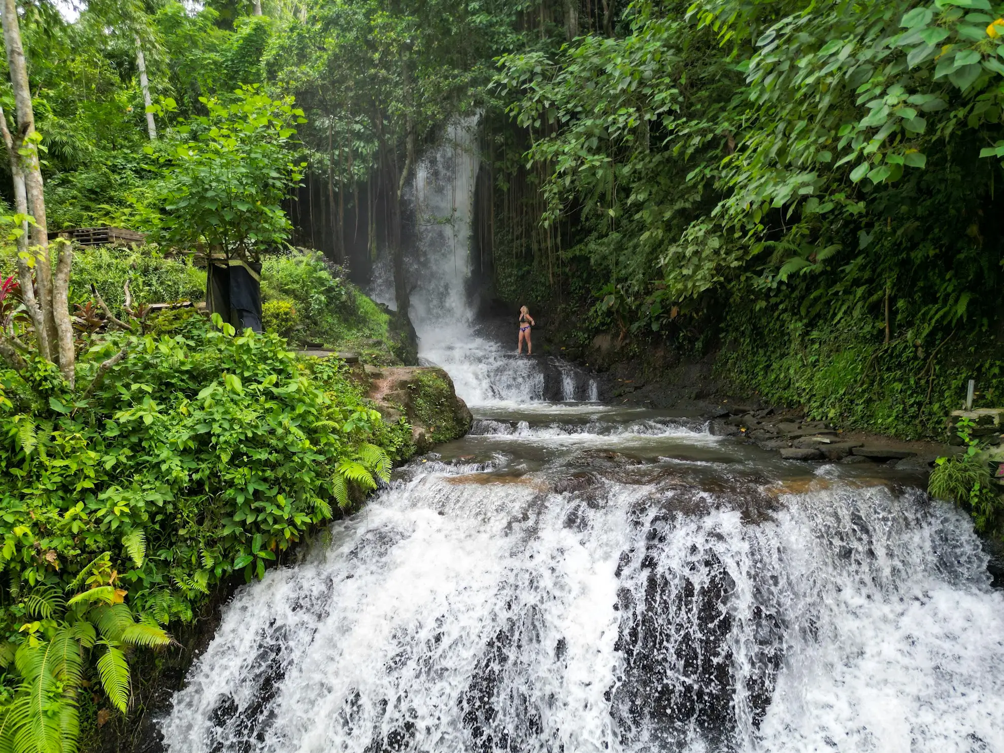 A woman standing at the cascading Uma Anyar Waterfall, one of the waterfalls near Ubud.