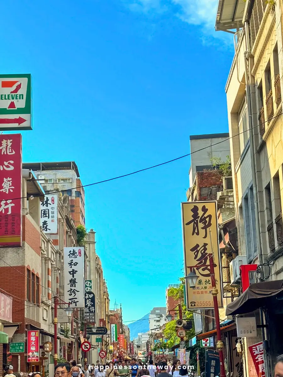 Bustling Dihua Street filled with people and various shops, with signs in Chinese characters hanging along the buildings.