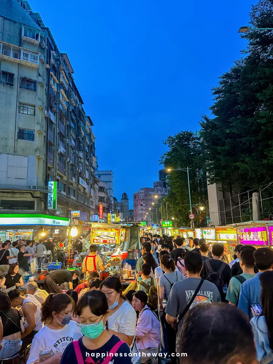 Crowded Ningxia Night Market in the evening, with people walking and buying food from various street vendors.