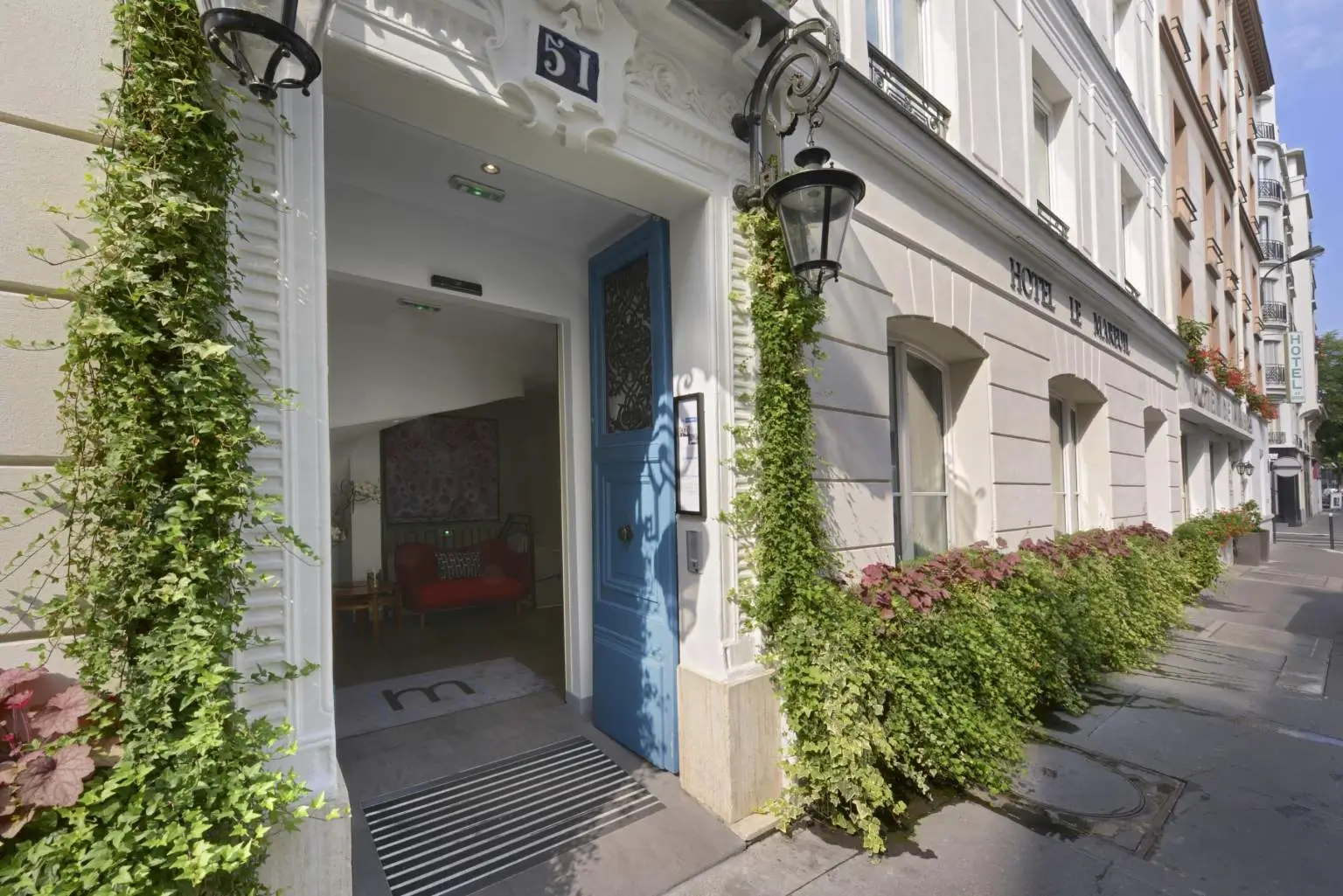 Boutique Hotel Le Mareuil entrance with a blue door, white exterior, and lush plants.