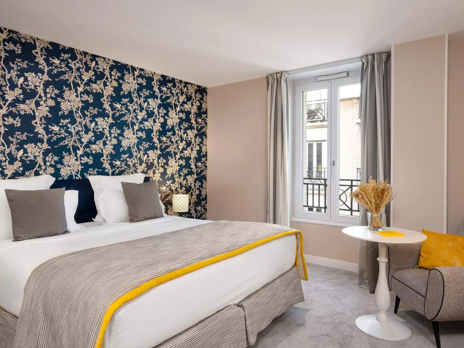 Boutique Hotel Le Mareuil room showcasing a printed blue wall with white flowers, complemented by a comfortable bed.