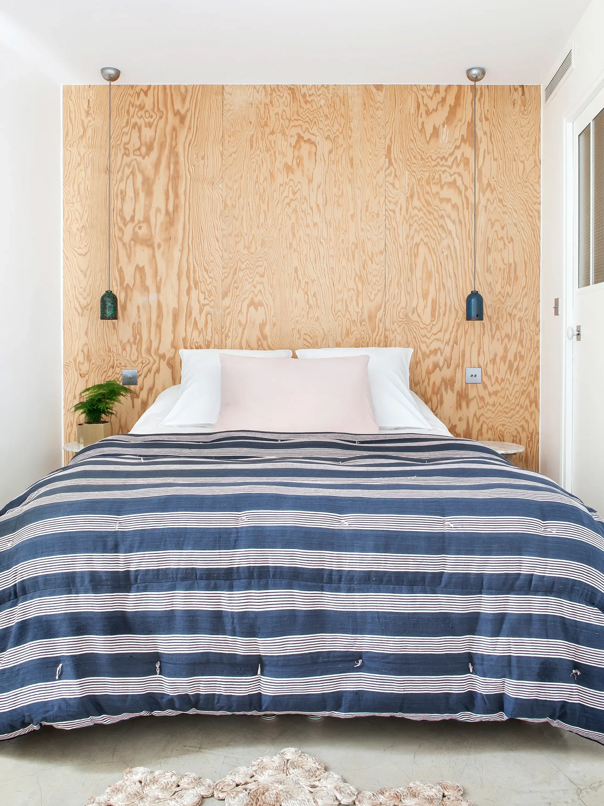 Cozy bed at Hotel Henriette, a quiet hotel in Paris, featuring a blue and white striped duvet.