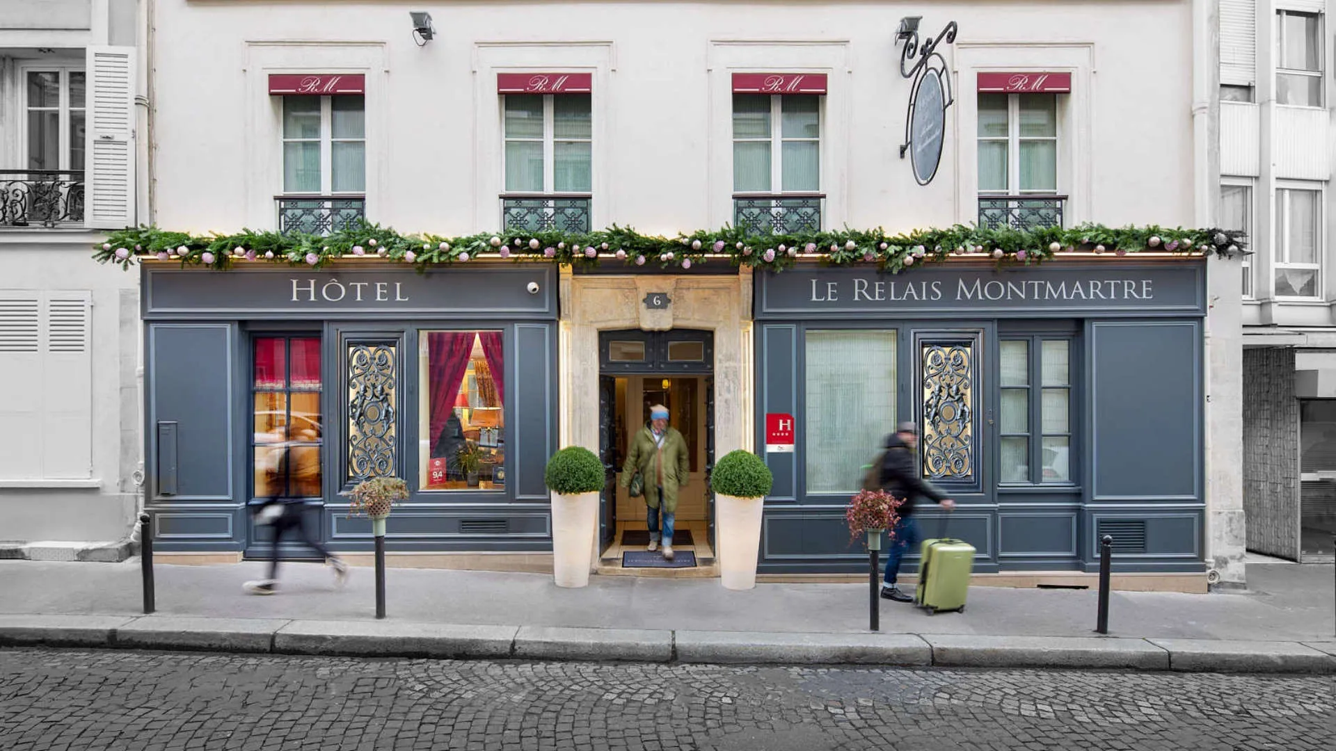 Quiet hotel in Paris, Hôtel Le Relais Montmartre entrance, showcasing a chic white and gray facade with 'Hôtel Le Relais Montmartre' written in front.