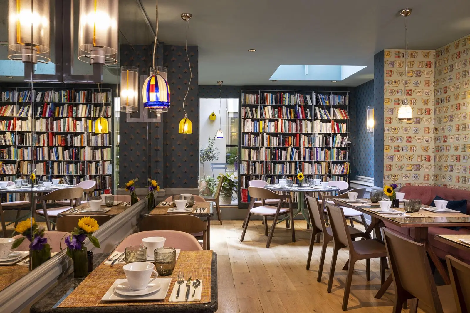 Quiet hotel in Paris with a charming breakfast area, featuring fresh flowers on the tables and cozy surroundings resembling a library full of books.