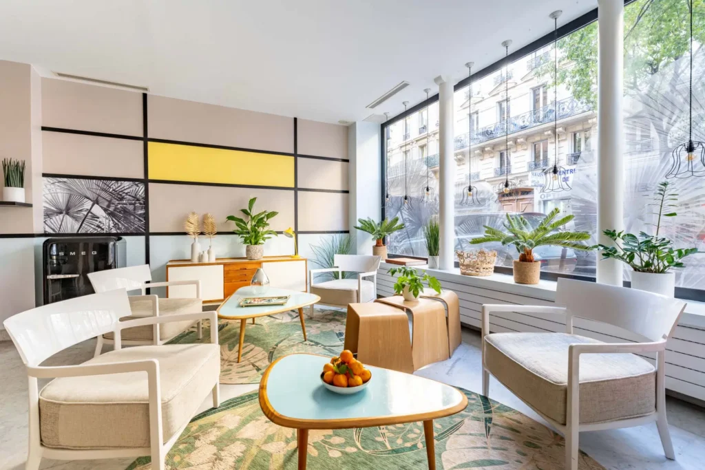 Hôtel Palm - Astotel lobby with modern tables, chairs, vibrant plants, and a bowl of fresh oranges.