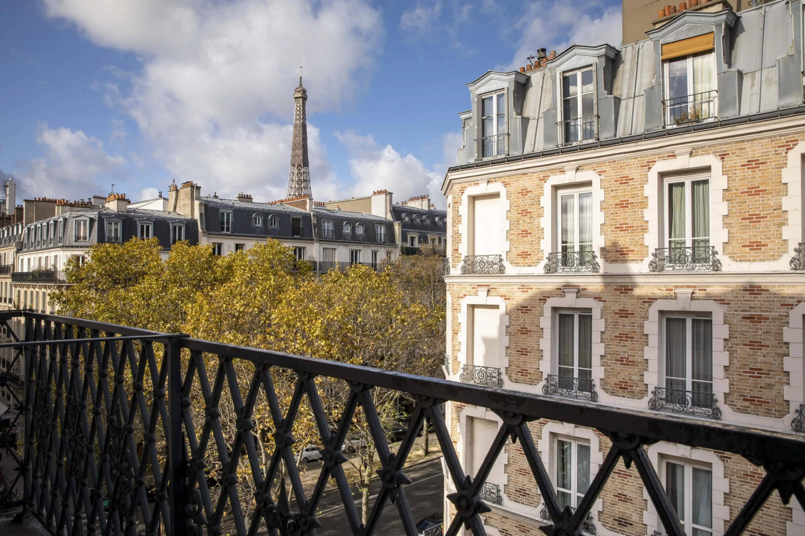 Balcony view from Hotel Relais Bosquet by Malone, showcasing a quiet Paris scene with the Eiffel Tower in the distance.