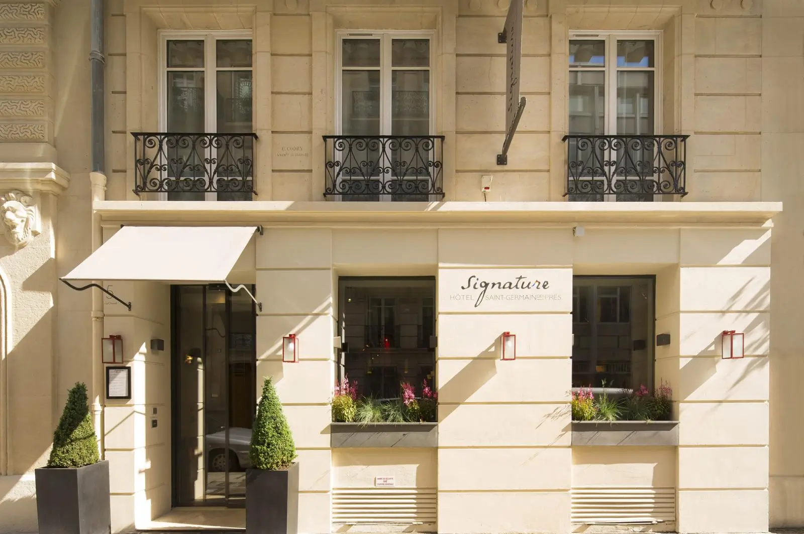 The cream-colored facade of Hôtel Signature Saint Germain des Prés, a quiet hotel in Paris, with classic Parisian architecture and elegant details.