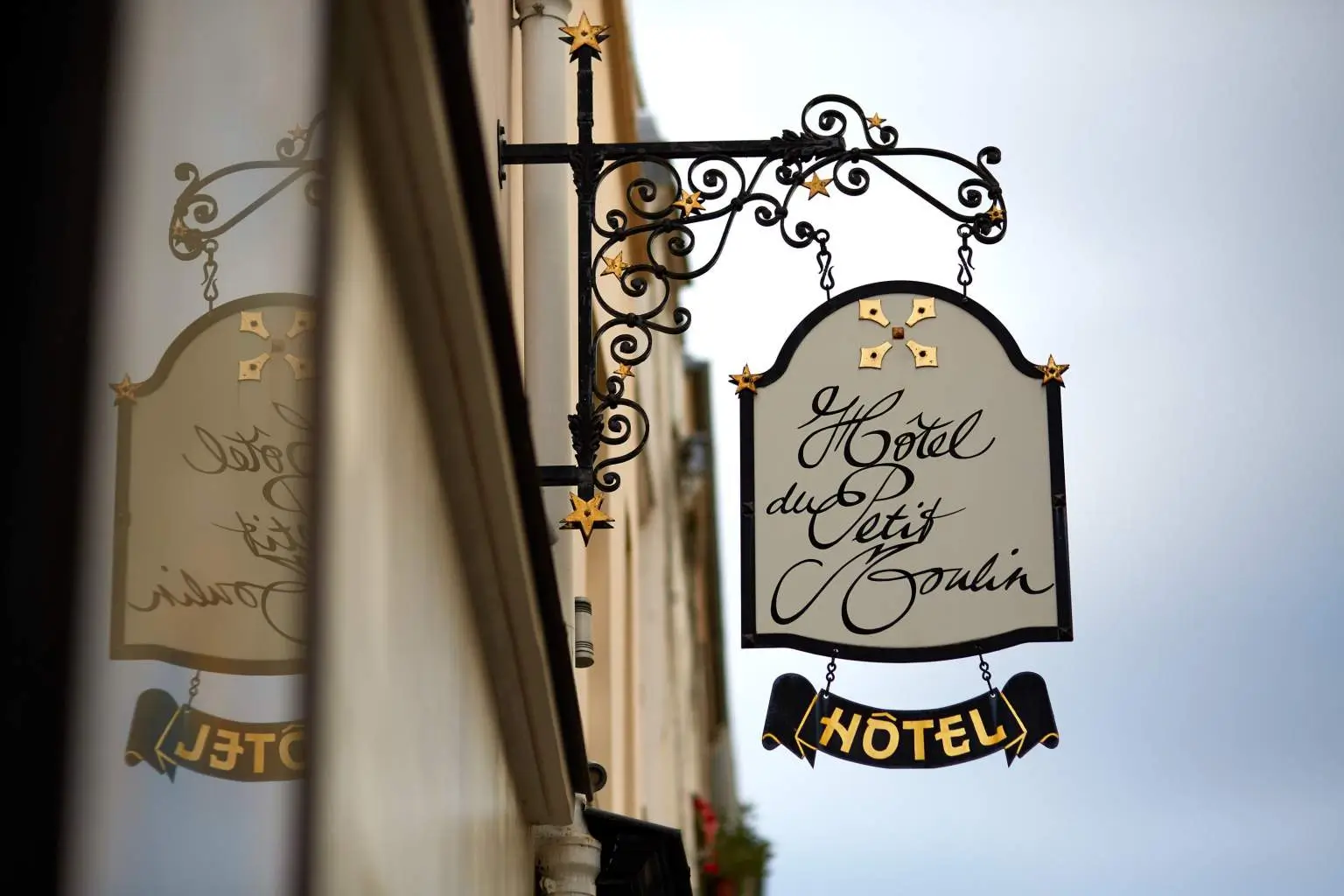 Exterior signage of Hotel du Petit Moulin Paris, a quiet hotel in Paris, featuring a classic design against the building's charming façade.