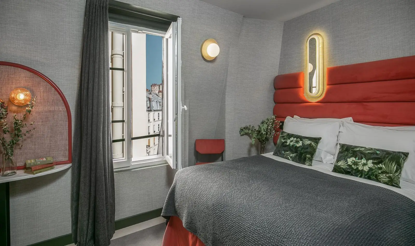 A cozy room at La Planque hotel in Paris, featuring a rich red interior with minimalist decor.