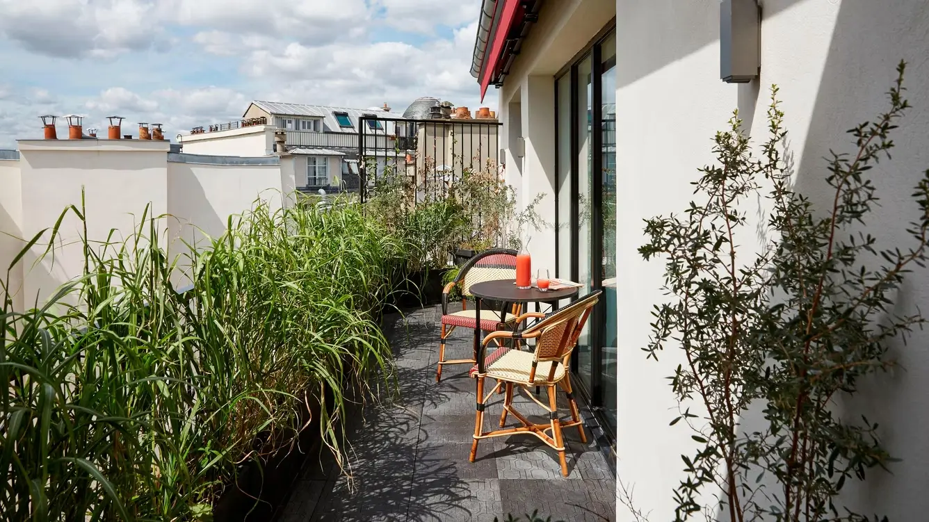 A private balcony at Le Roch Hotel & Spa in Paris, adorned with lush plants and two comfortable chairs, creating a tranquil outdoor space perfect for unwinding at this quiet hotel in Paris.