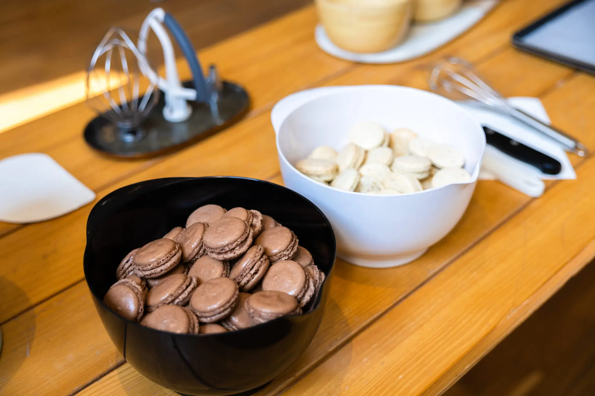 Bowls of chocolate and vanilla macarons with baking utensils on a table in a baking class in Paris.