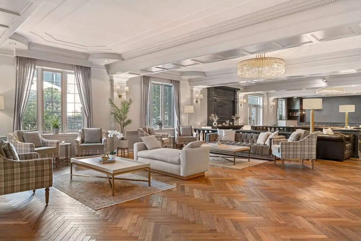 The tranquil lobby of the Madison Hôtel, a quiet hotel in Paris, boasts elegant wood floors, stylish checkered sofas in white and brown, and large windows offering views of the Parisian streets outside.