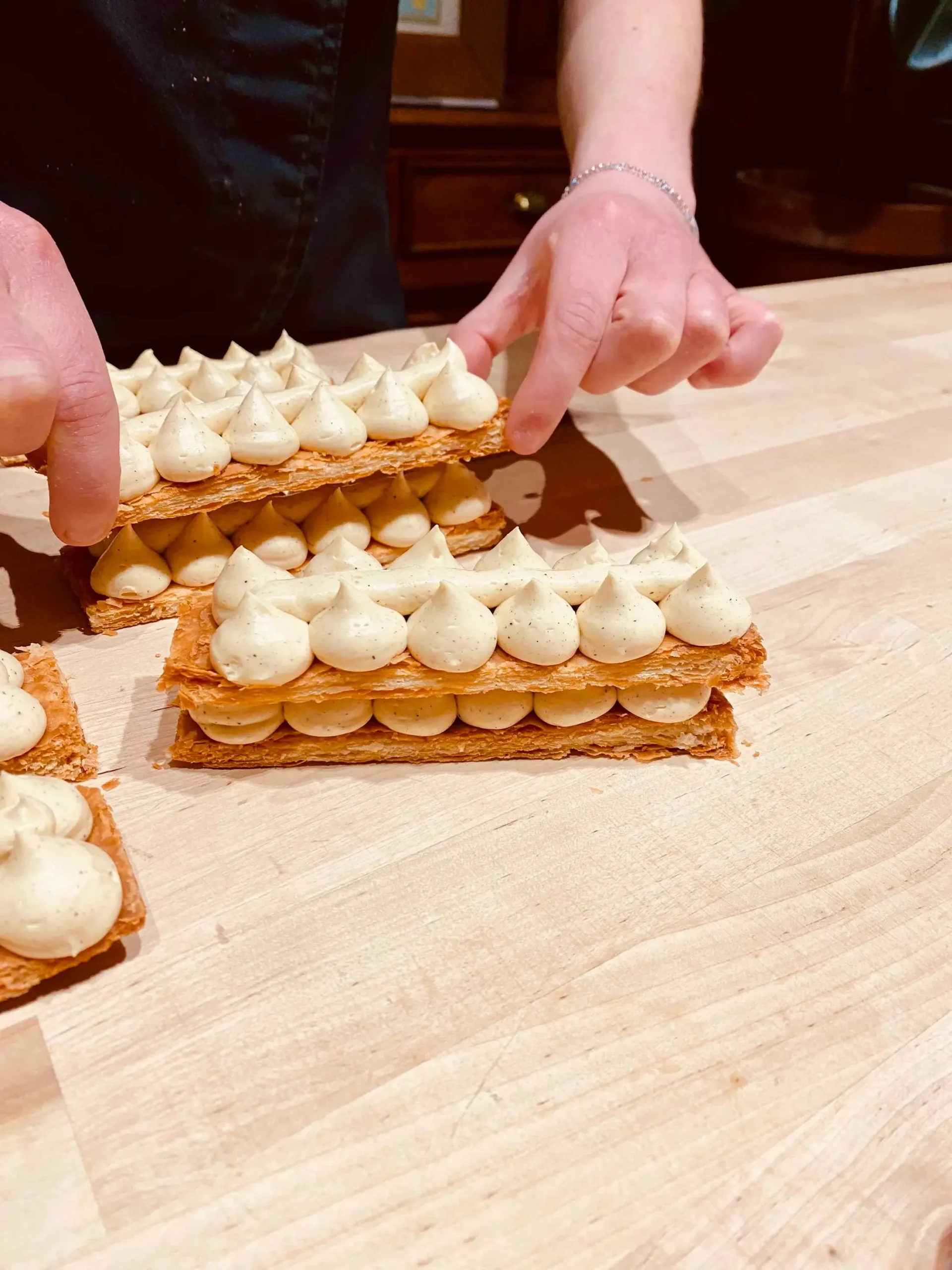 A participant in a pastry class in Paris assembling a Mille Feuille Napoléon