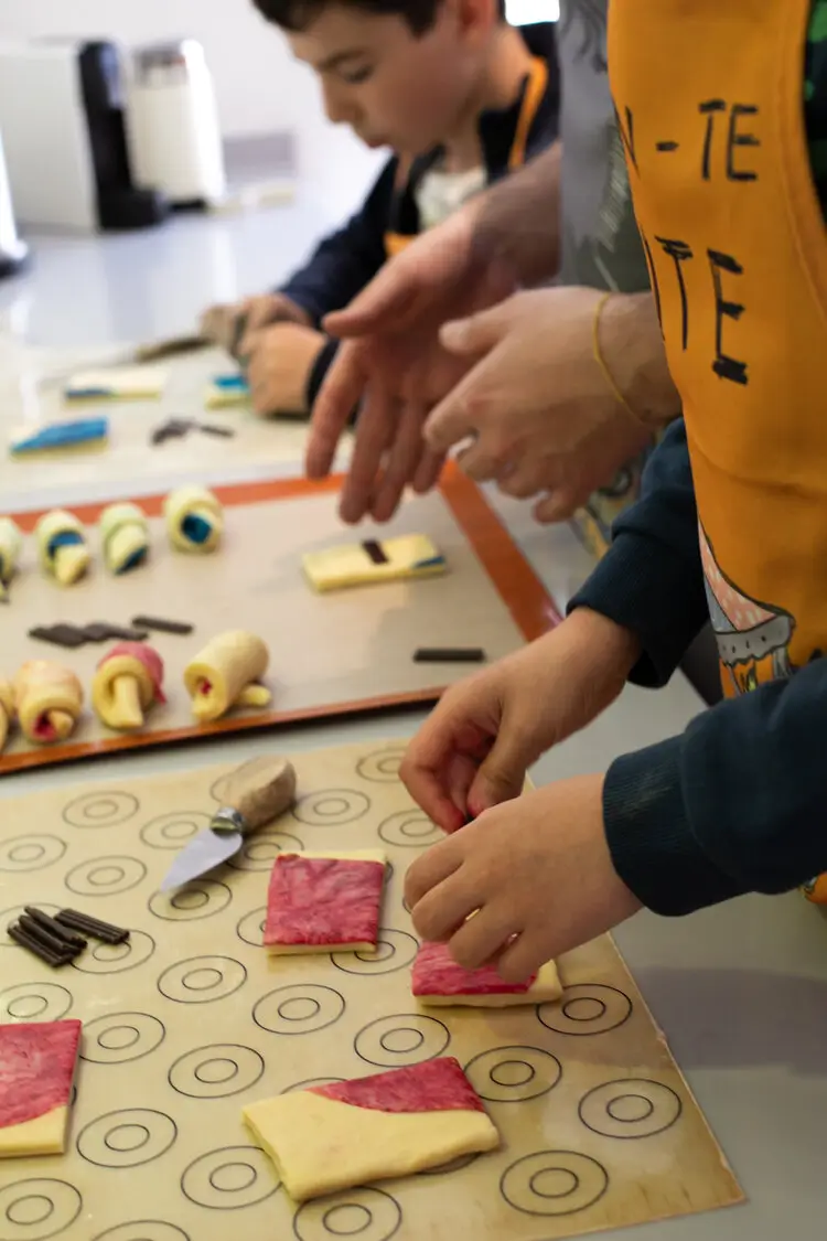 Kids in a baking class in Paris assembling colorful croissants.