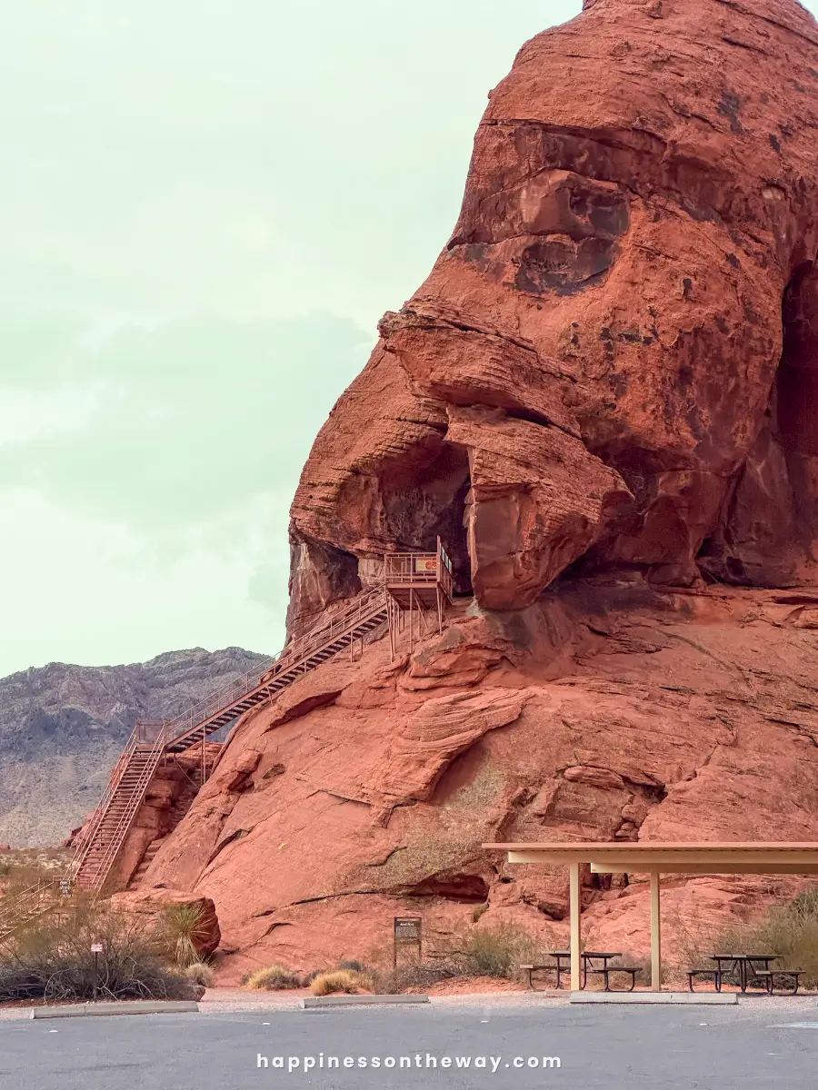 A view of Atlatl Rock in Valley of Fire State Park, showcasing red sandstone formations with a staircase leading up to ancient petroglyphs.