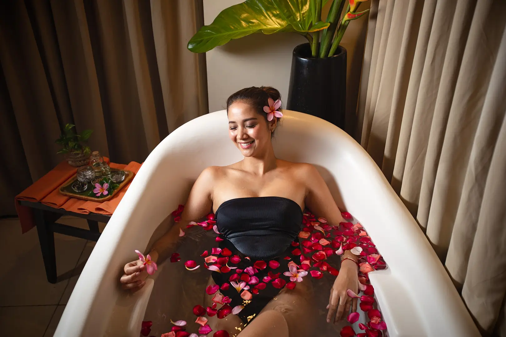 A woman relaxing in a bathtub filled with rose petals at Terra Wellness Spa in Boracay.