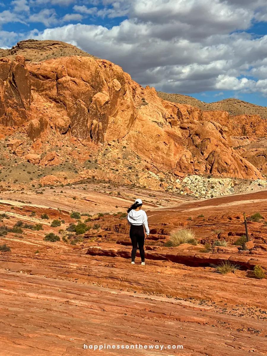 Me walking across the vibrant orange and red rock formations in Valley of Fire State Park.