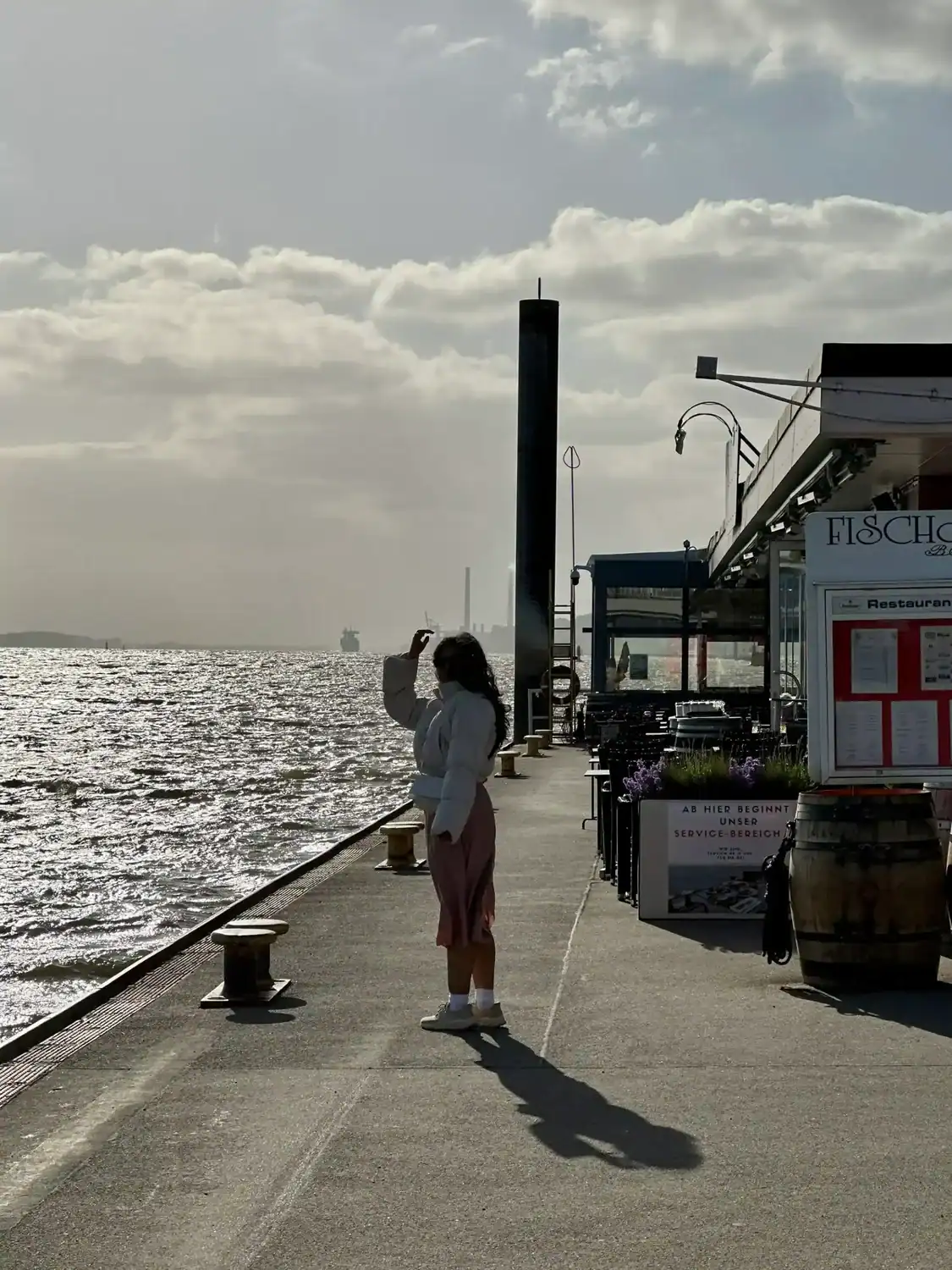 A woman standing on the dock and watching the wavs in of Hamburg, one of the benefits of slow travel