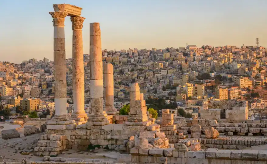 Ancient Roman ruins of the Temple of Hercules in Amman, Jordan, with tall, weathered stone columns standing prominently in the foreground.
