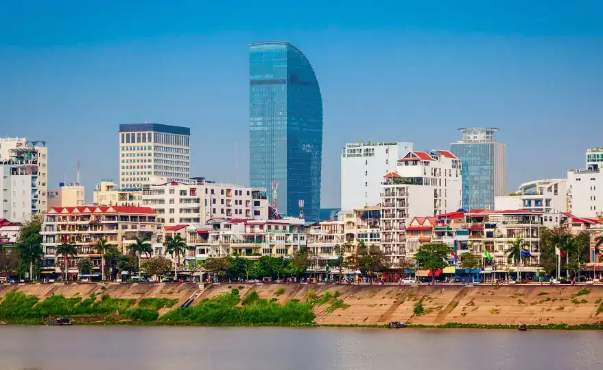 Cityscape of Phnom Penh, Cambodia, featuring a mix of modern and traditional architecture along the riverfront.