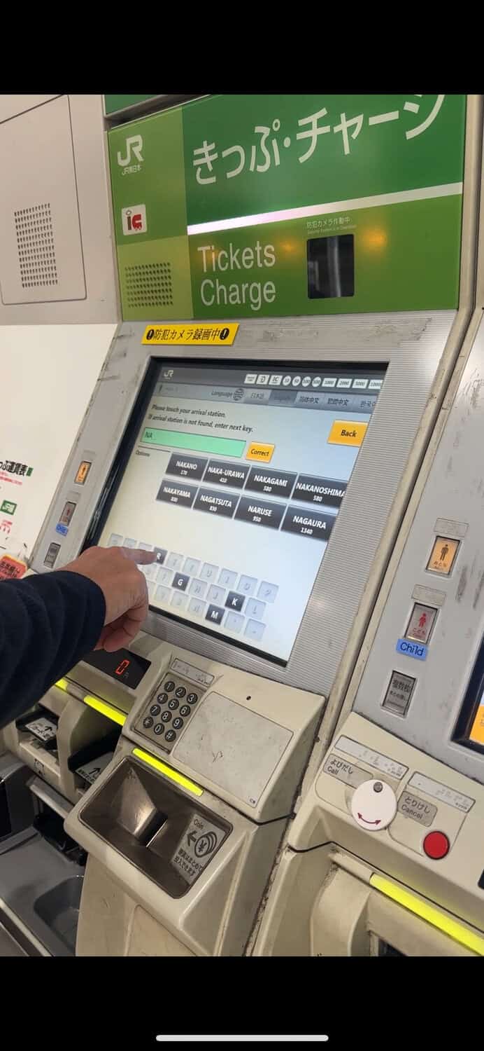 Close-up of a person using a ticket machine at a Japan train station.