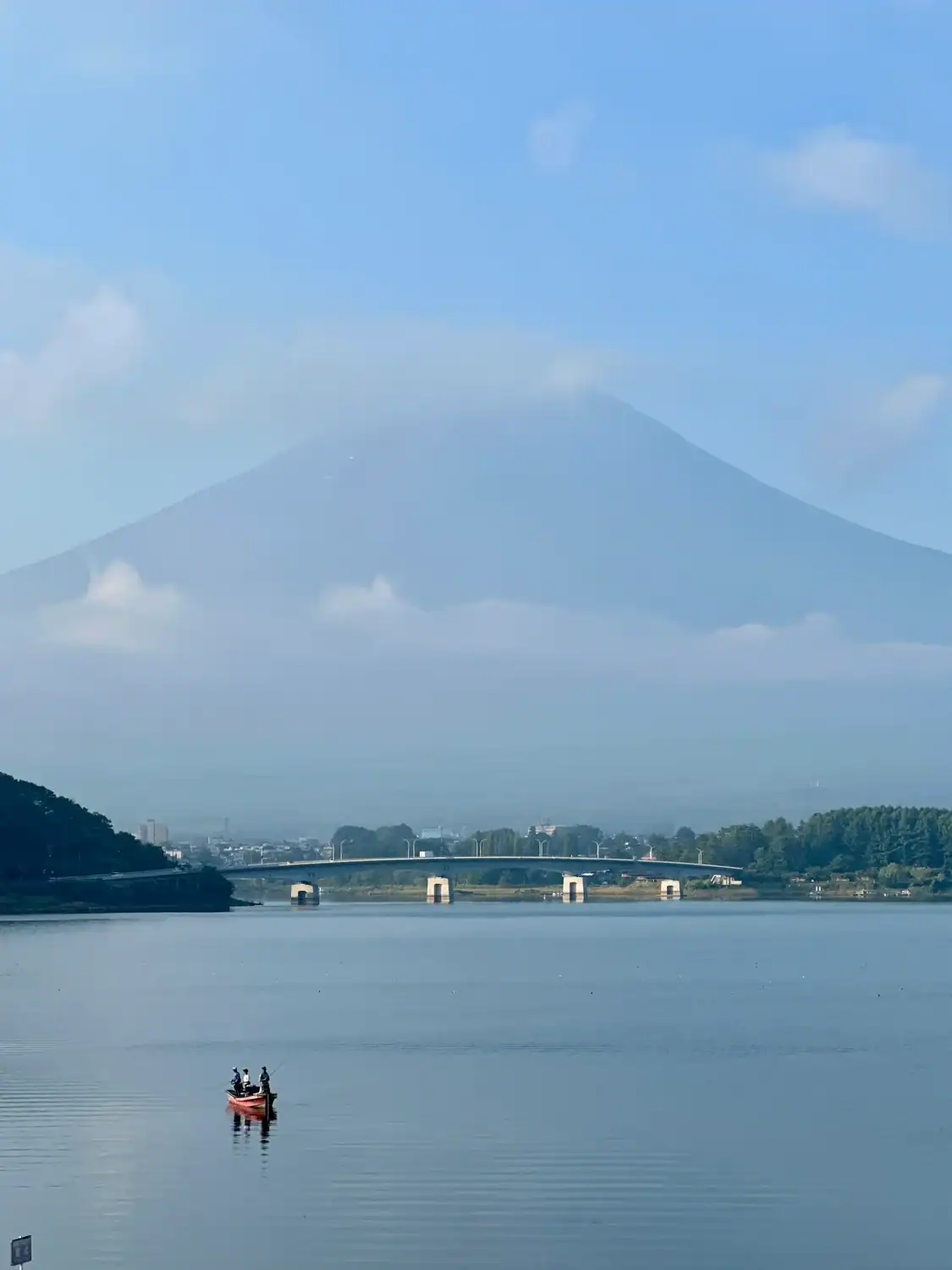 View of Mt. Fuji with soft clouds and a small boat on the lake, taken during a road trip in Japan.