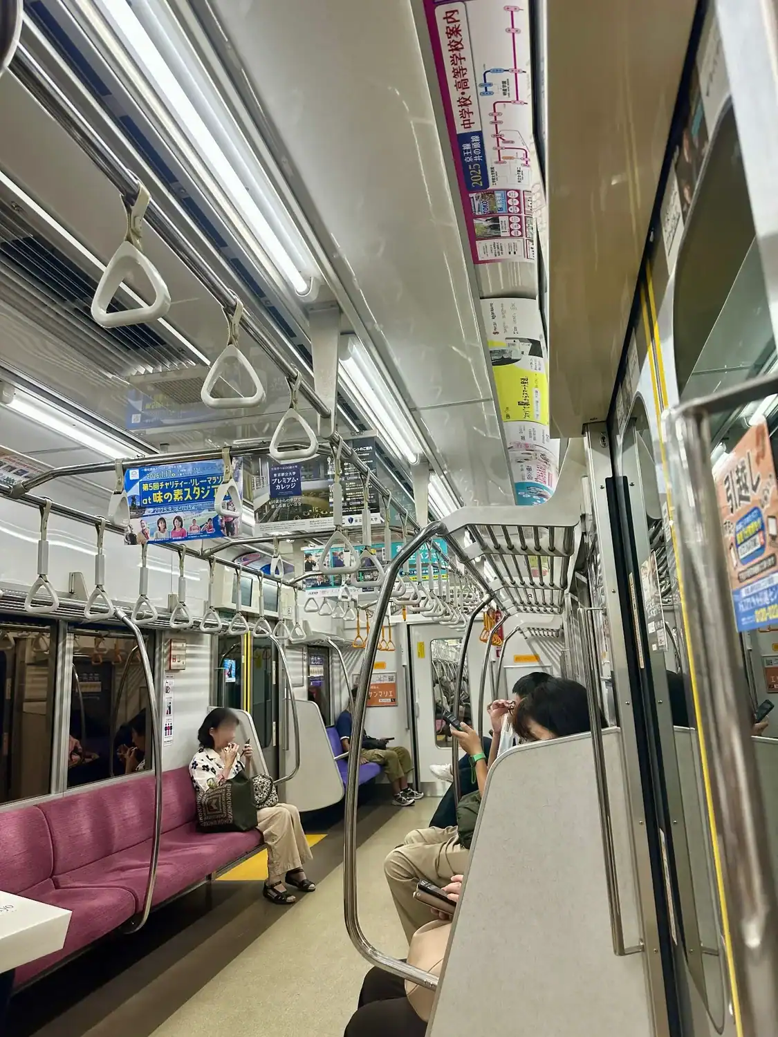 Interior of a Tokyo Metro train with seated passengers and overhead route maps