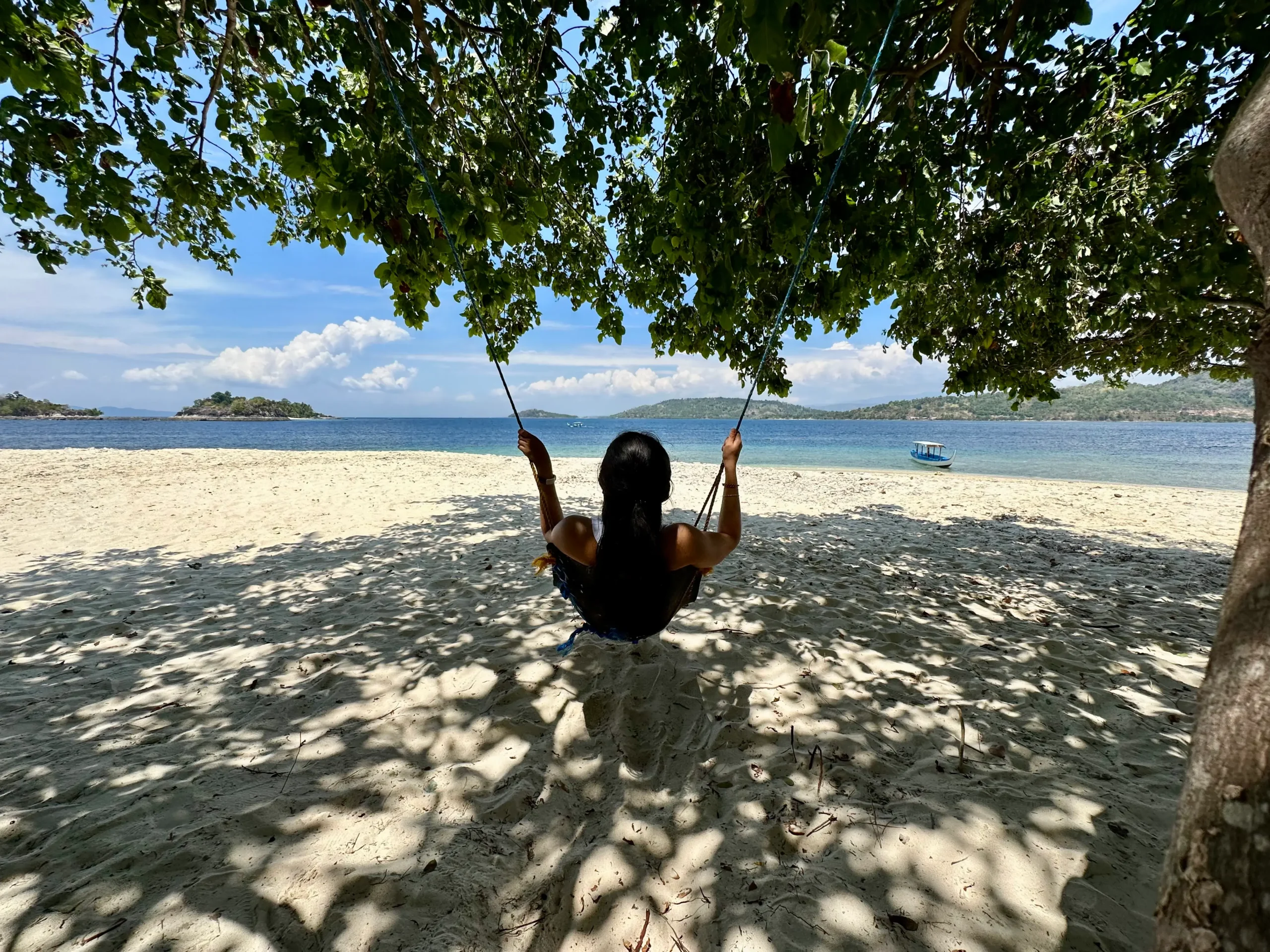 Travel blogger relaxing on a swing at a tropical beach, symbolizing the freedom and flexibility of earning passive income through the Stay22 affiliate program