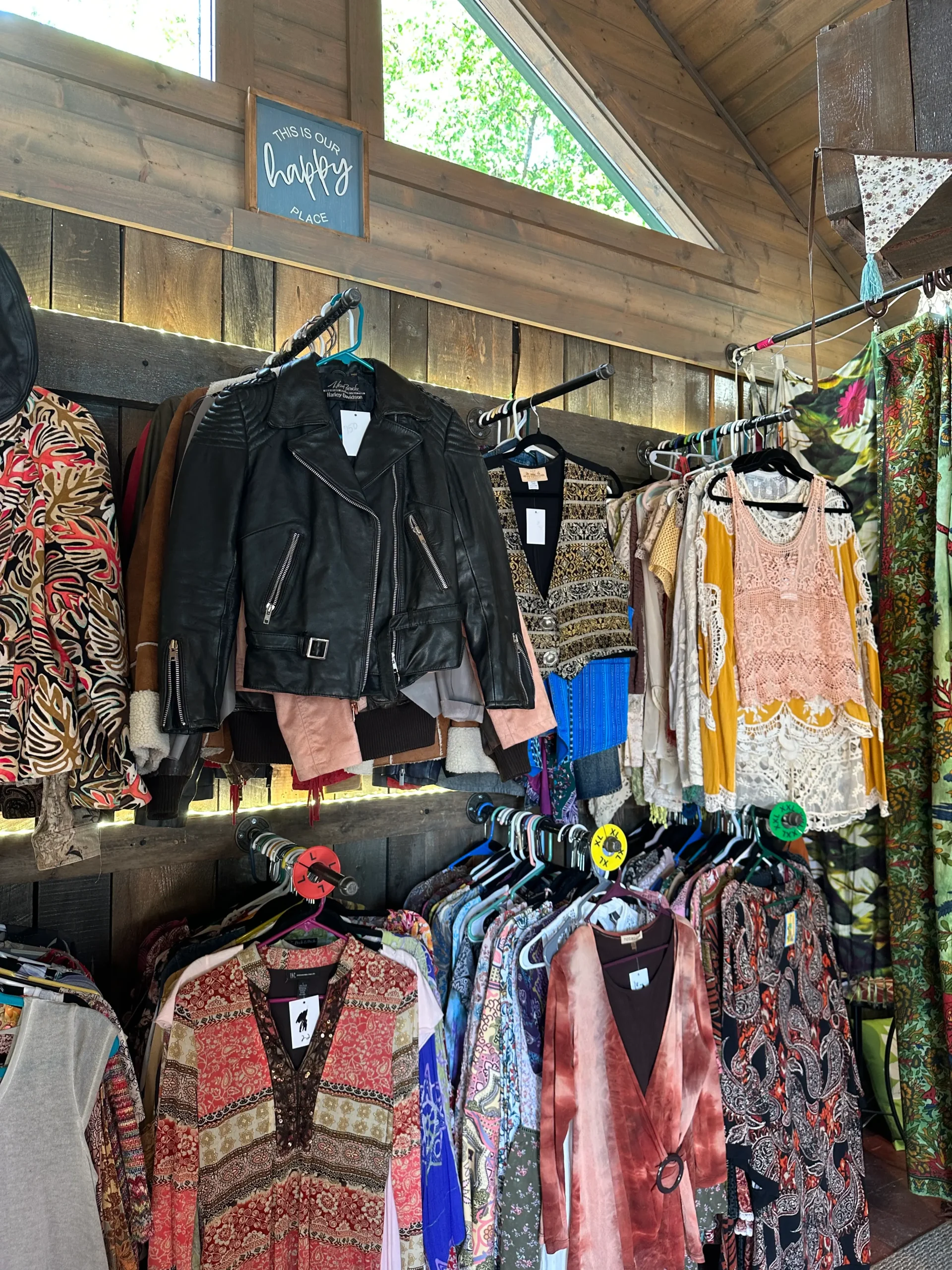 Clothing racks at Beadberry Patch displaying a leather jacket and colorful blouses with Indigenous-inspired designs.