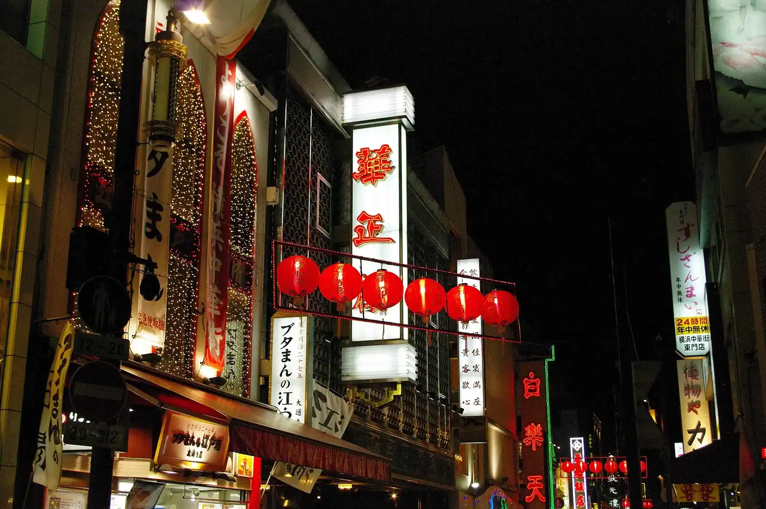 Yokohama Chinatown at night with red lanterns strung across storefronts and glowing neon signs with Japanese and Chinese characters