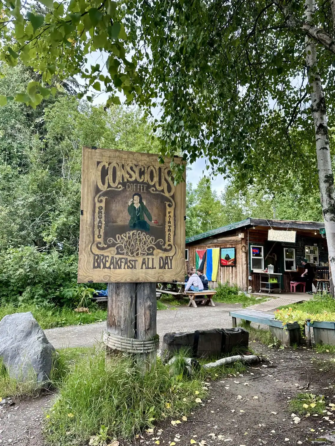 A wooden, hand-carved sign leading to Conscious Coffee, one of the many places to eat in Talkeetna.
