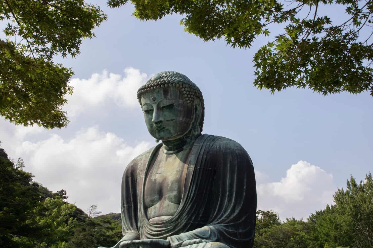 The Great Buddha of Kamakura, a 13th-century bronze statue sitting in an open-air setting surrounded by green foliage