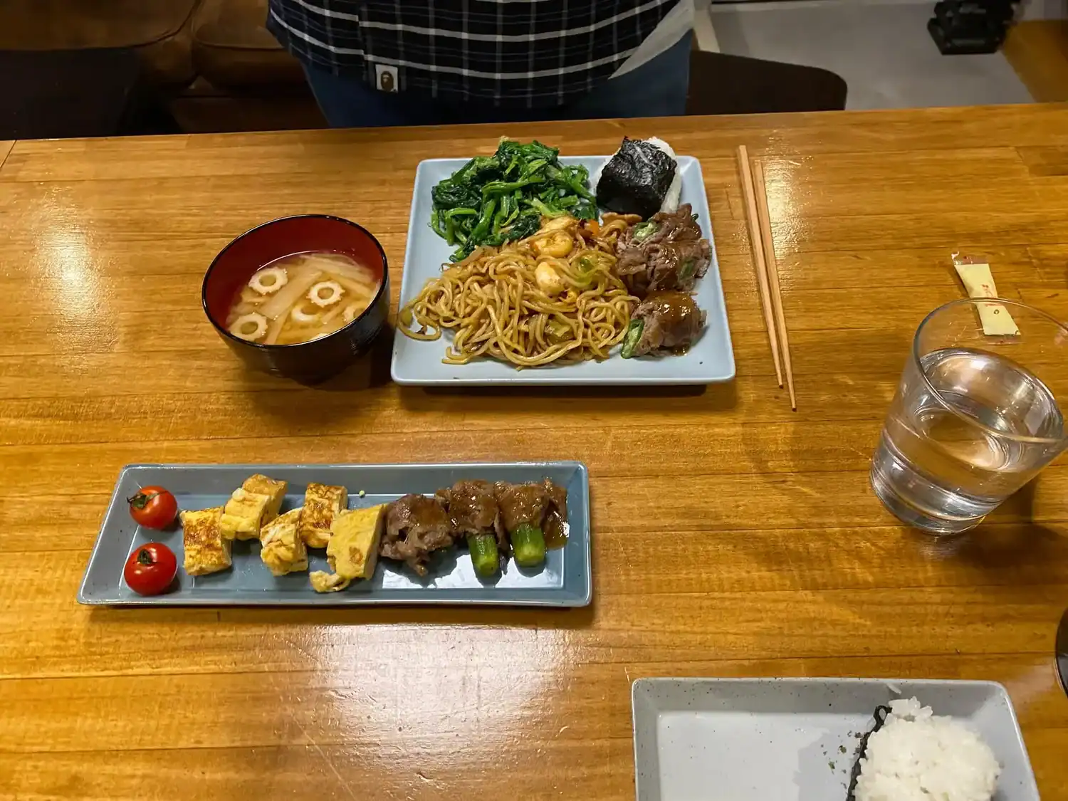 raditional Japanese home-style meal prepared during a Tokyo cooking class, featuring yakisoba noodles, miso soup, tamagoyaki, vegetables, and rice on a wooden table.