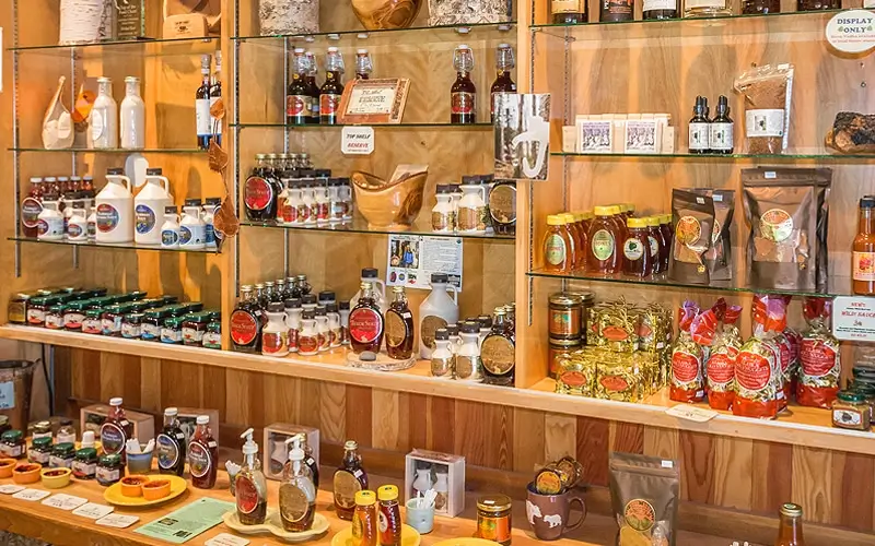 Shelves stocked with birch syrup bottles, jams, and other local products inside an Alaskan gift shop.