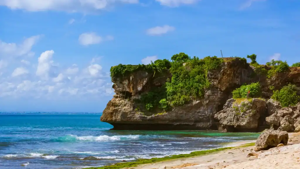 Balangan Beach cliffs overlooking turquoise water and gentle surf in Uluwatu.
