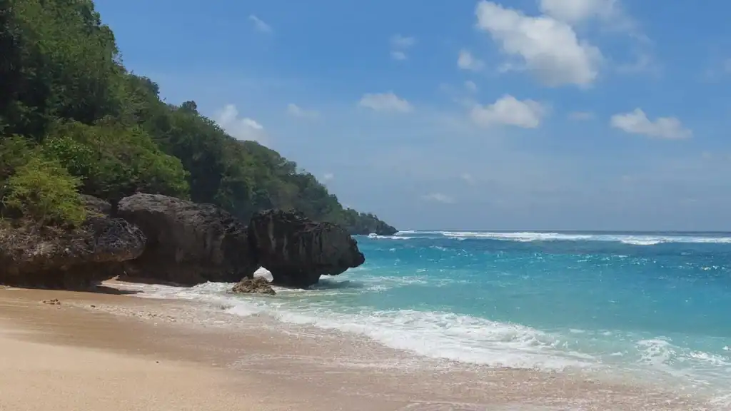 Melasti Beach framed by tall white cliffs and turquoise waves in Uluwatu, Bali.