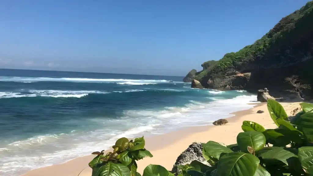 Nyang Nyang Beach with untouched sand and rolling waves under bright blue skies.