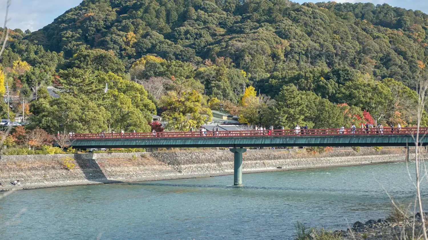 A red bridge crossing the Uji River with forested hills in the background.